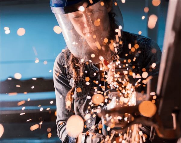 woman wearing mask and welding with sparks flying